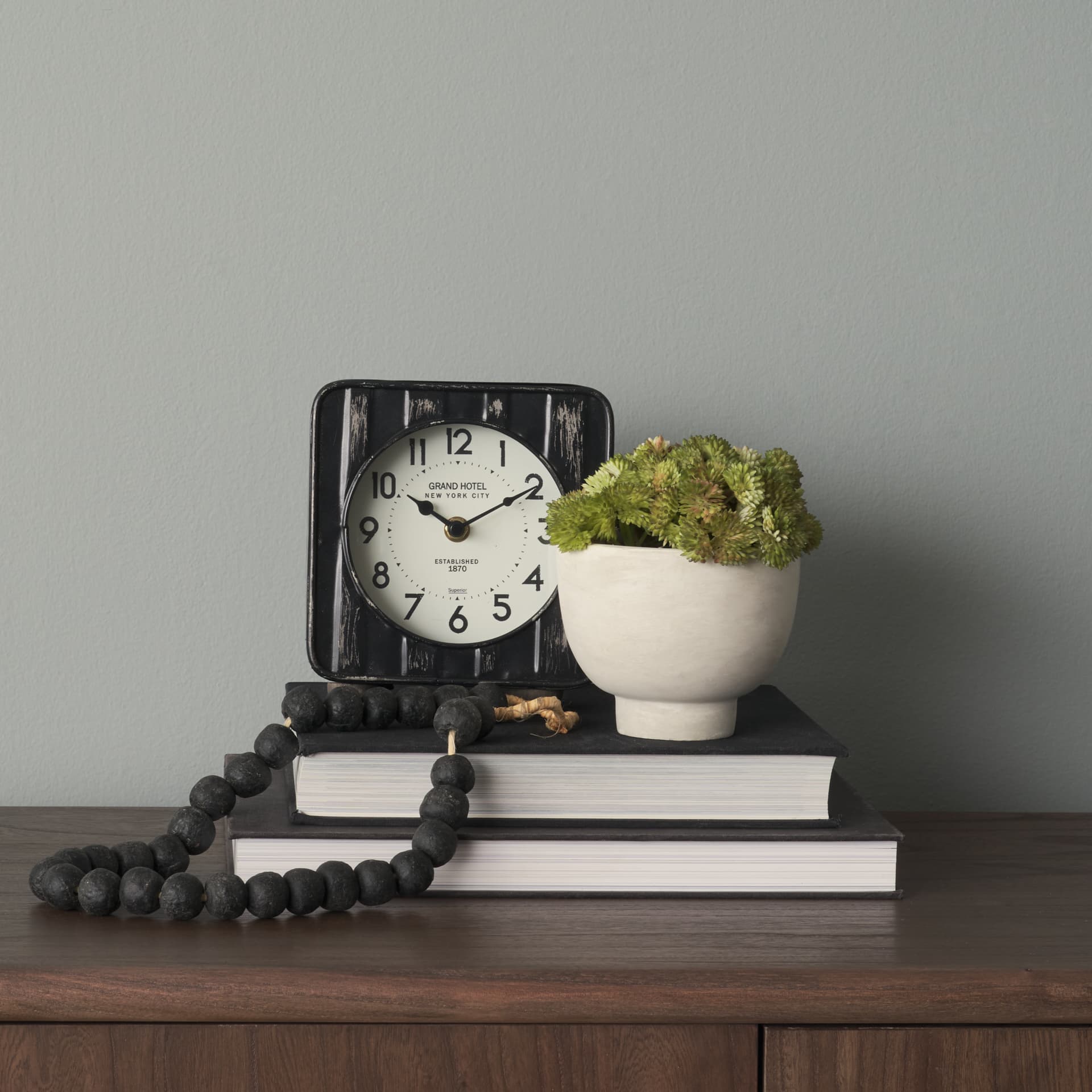 Karl 6.0L x 3.0W x 6.8H Rustic Black Iron Rounded Square Table Clock — in a styled room