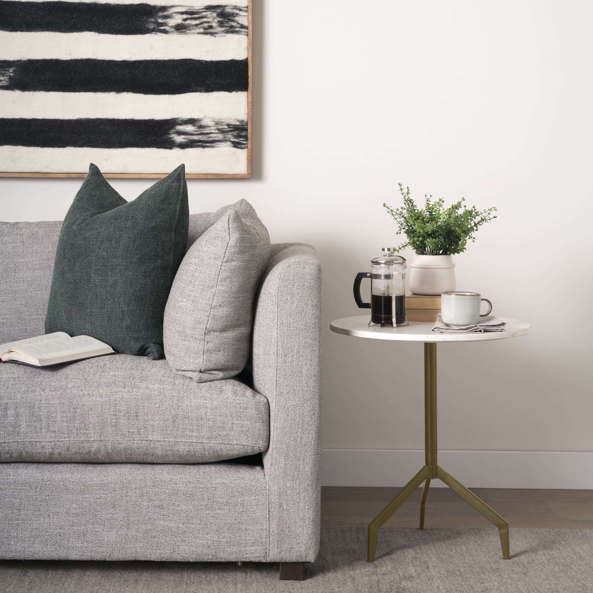 Serre Marble Top 3 Prong Gold Metal Base End Table — in a styled room